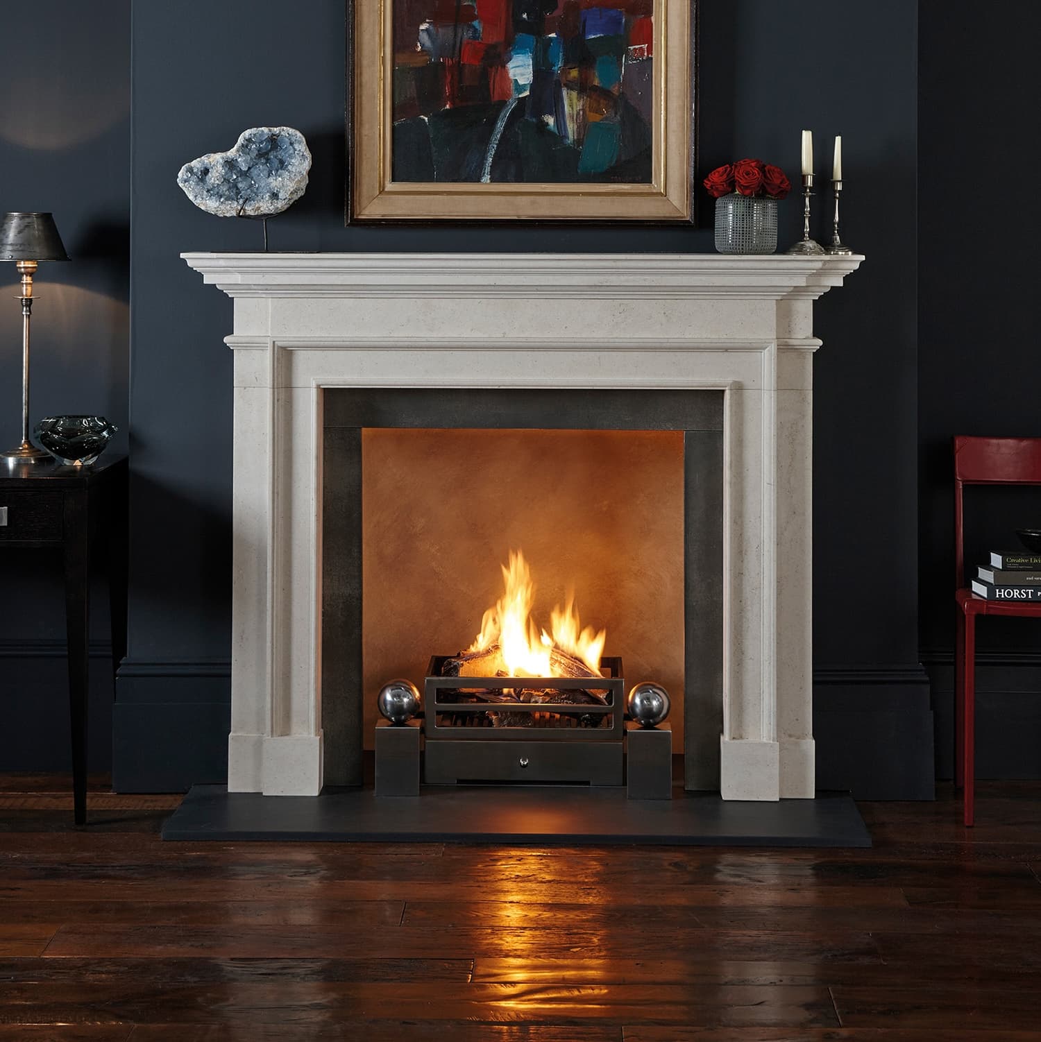 Limestone fireplace surround with a real fire in a dark-painted room
